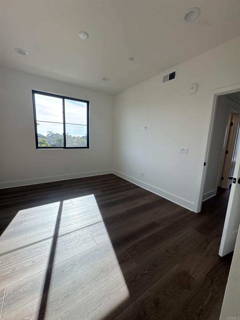 1105 Catania Court, Unit 201 Encinitas, CA 92024 - Photo 8 of 19 a view of empty room with wooden floor and fan
