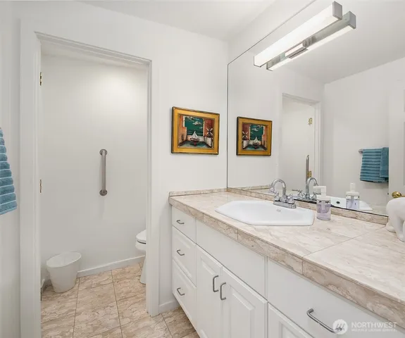 a bathroom with a granite countertop sink mirror vanity and toilet
