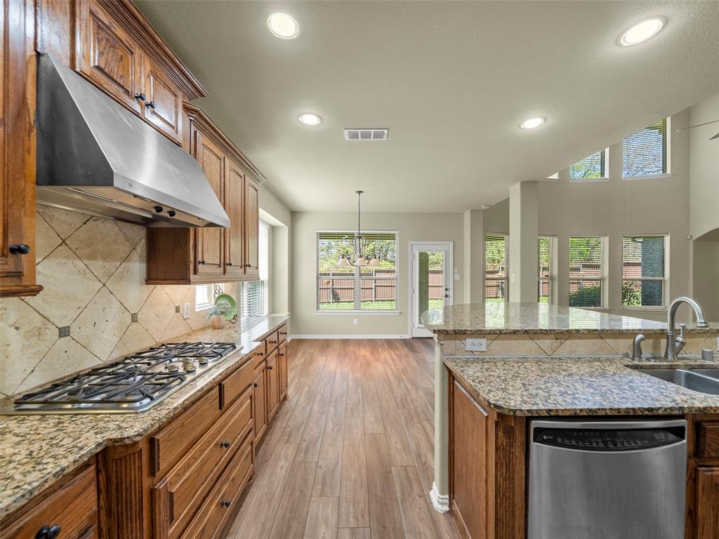 5143 Stream Crest Way Fairview, TX 75069 - Photo 13 of 35 Kitchen with light stone countertops, stainless steel appliances, wood finish cabinetry, and light wood-style floors