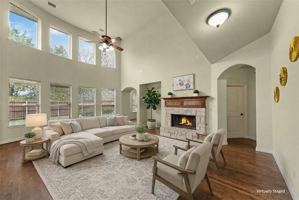 5143 Stream Crest Way Fairview, TX 75069 - Photo 7 of 35 Living area with arched walkways, ceiling fan, dark wood finished floors, a fireplace, and a high ceiling