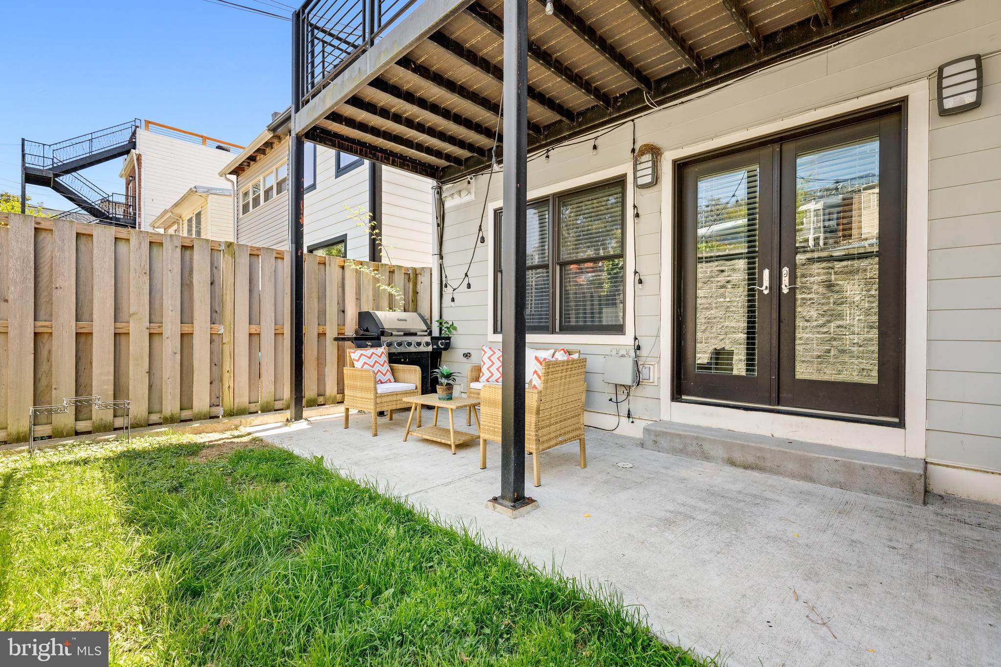 1337 Spring Road Northwest, Unit 1 Washington, DC 20010 - Photo 35 of 39 a porch with a table and chairs next to a yard