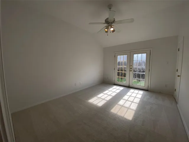 a view of an empty room with window and chandelier fan