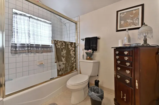a bathroom with a toilet a sink a bath tub and next to a window