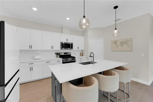 a large kitchen with sink a counter and chairs