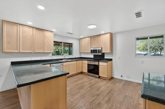 a kitchen with granite countertop a stove a sink and a refrigerator