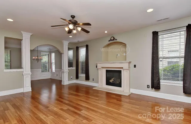 a view of an empty room with wooden floor fireplace and a window