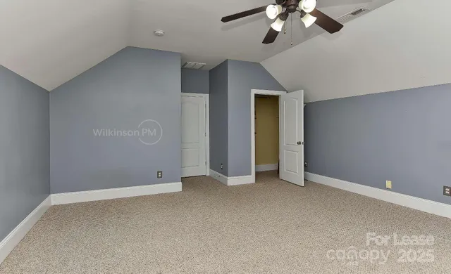 a view of an empty room with a chandelier fan