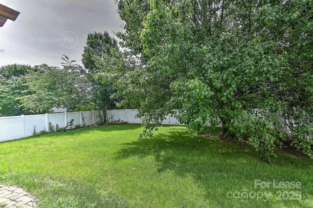 a view of a yard with a fence and trees