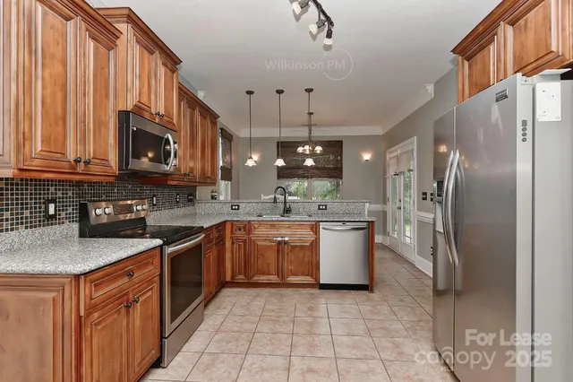 a large kitchen with stainless steel appliances granite countertop a stove a sink dishwasher a refrigerator and a microwave oven