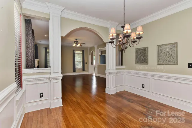 a view of a hallway with wooden floor and chandelier