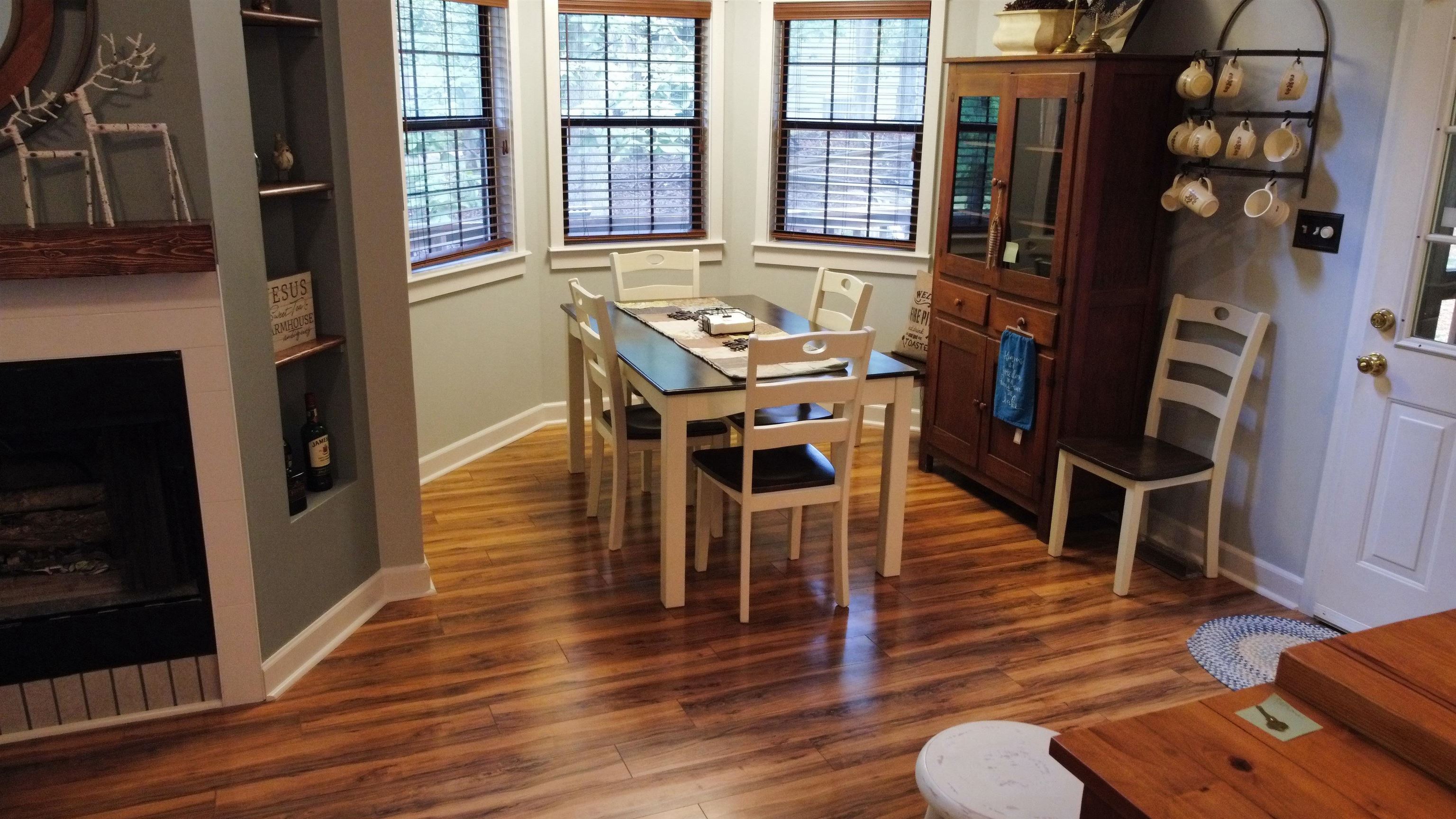 275 Bryson Harbor Road Counce, TN 38326 - Photo 17 of 23 Corner dining area featuring wood-finish flooring, multiple windows with blinds, and a built-in fireplace with a wood mantle and recessed shelving