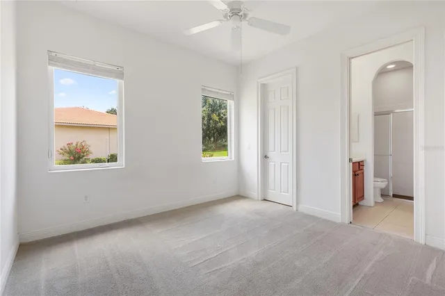 an empty room with a ceiling fan and carpet