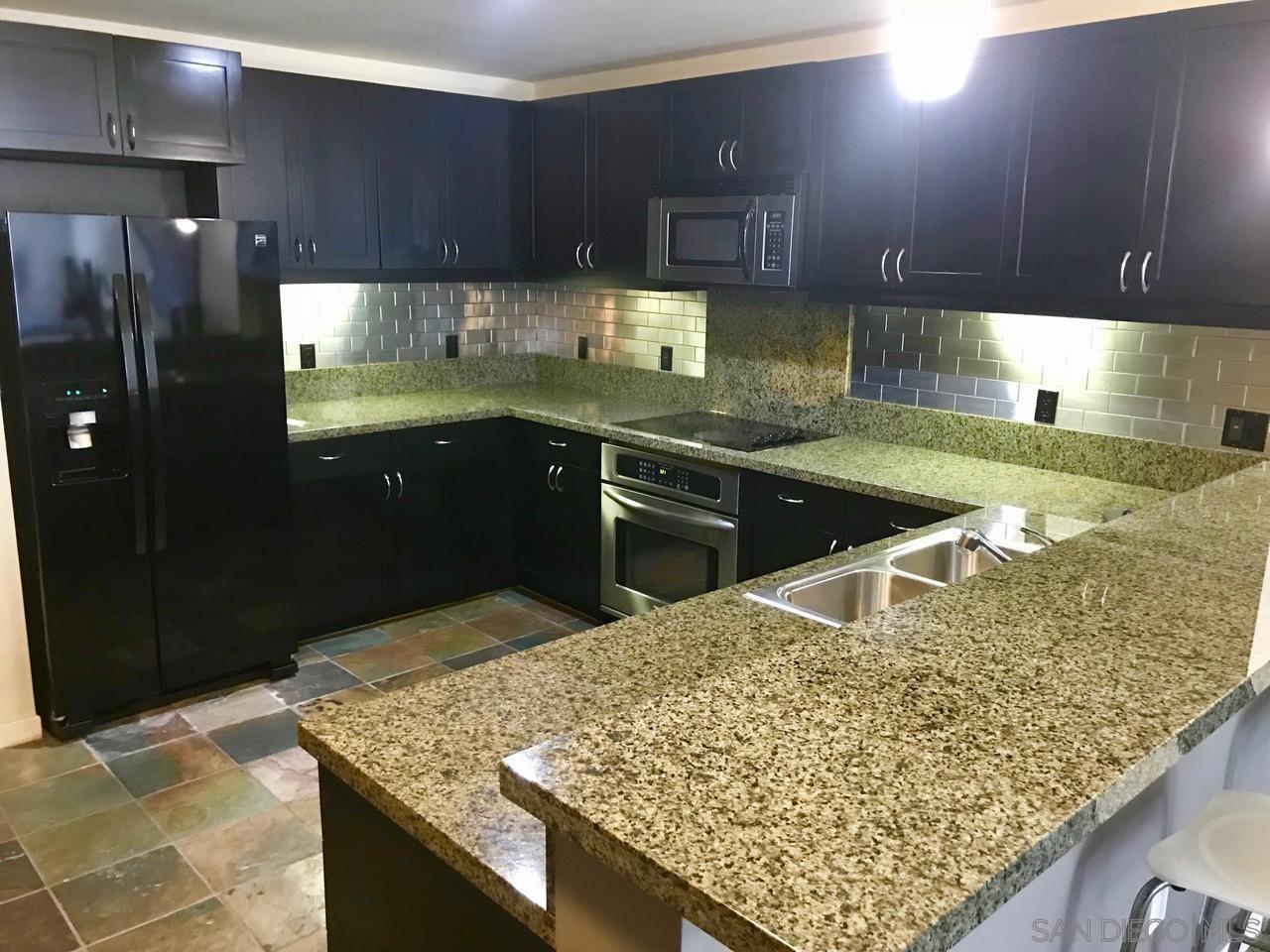 a kitchen with kitchen island granite countertop a sink stove and refrigerator