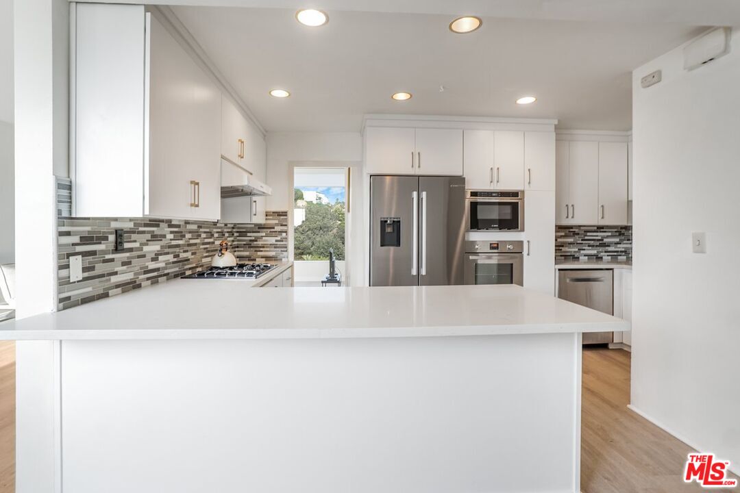 17350 Sunset Boulevard, Unit PH2 Pacific Palisades, CA 90272 - Photo 11 of 36 a large kitchen with stainless steel appliances a refrigerator and a stove top oven