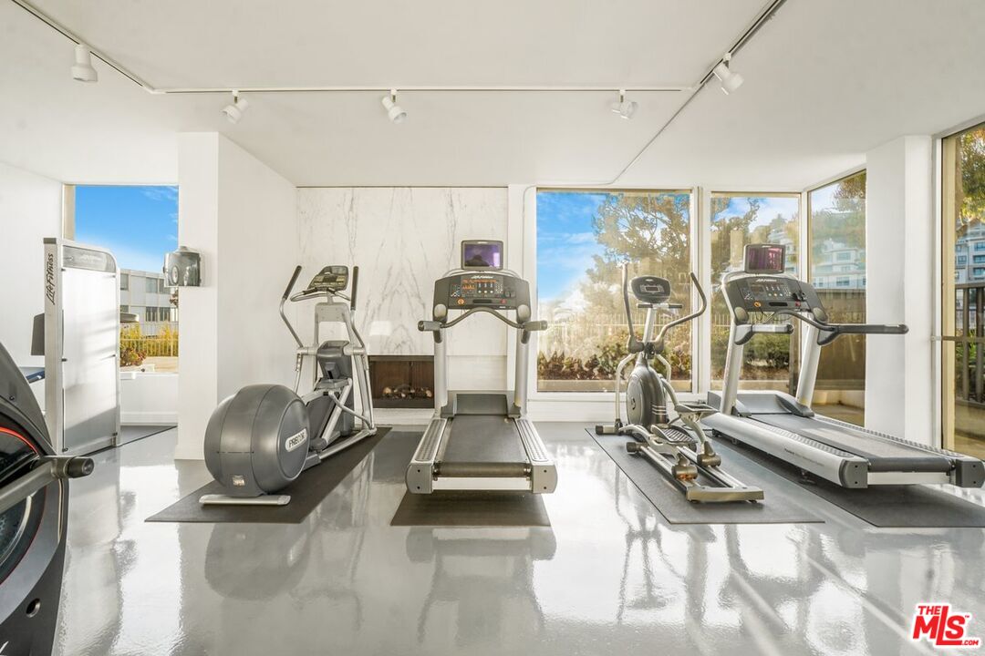 17350 Sunset Boulevard, Unit PH2 Pacific Palisades, CA 90272 - Photo 24 of 36 a room with gym equipment and large windows
