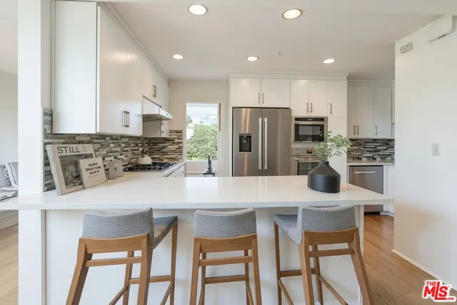 a kitchen with stainless steel appliances a dining table chairs and refrigerator