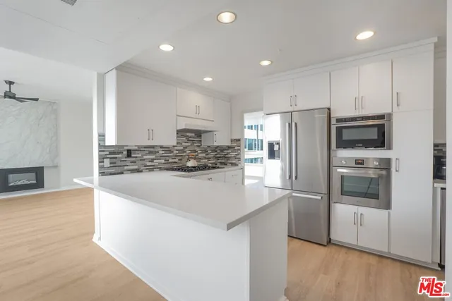 a kitchen with stainless steel appliances granite countertop a refrigerator and a stove top oven