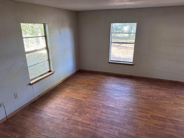 1343 Hillard Street Paris, TX 75460 - Photo 5 of 10 Empty room with dark wood-type flooring, healthy amount of natural light, and a textured wall
