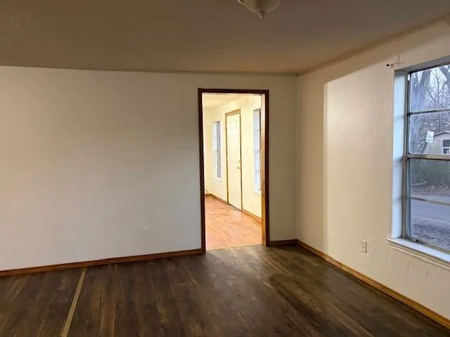 a view of an empty room with wooden floor and a window
