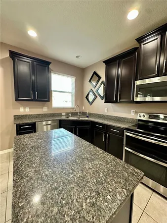 a kitchen with stainless steel appliances kitchen island granite countertop a stove and a sink