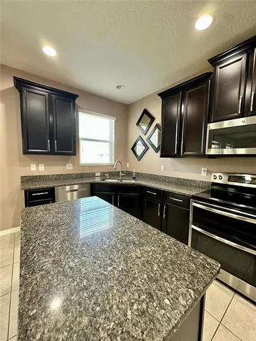 a kitchen with stainless steel appliances kitchen island granite countertop a stove and a sink