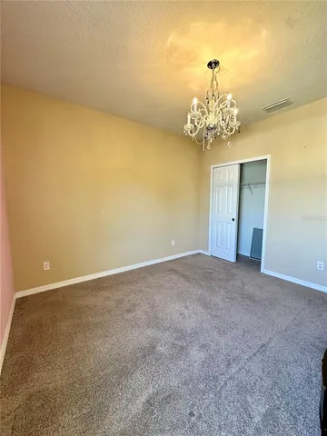 a view of an empty room with a chandelier fan