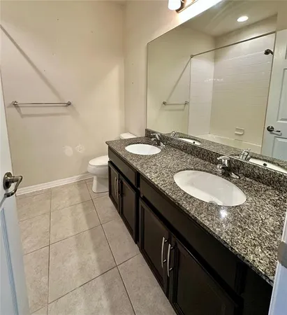 a bathroom with a granite countertop sink a toilet and a mirror