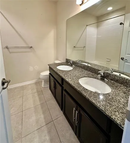 a bathroom with a granite countertop sink a toilet and a mirror