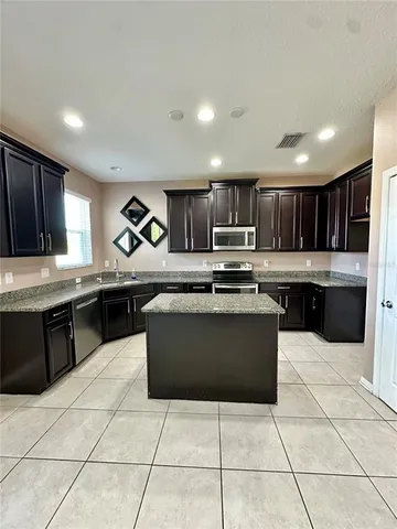 a large kitchen with granite countertop a stove a microwave oven and a sink