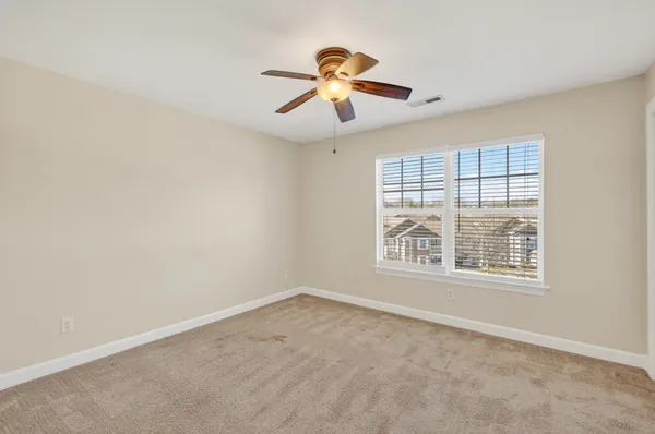 an empty room with closet and a chandelier fan