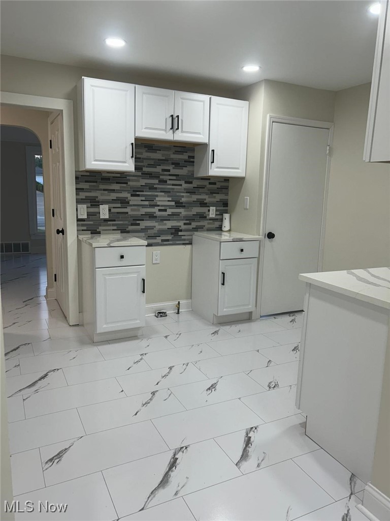 15410 Turney Road Maple Heights, OH 44137 - Photo 15 of 46 Kitchen featuring white cabinetry, decorative backsplash, arched walkways, recessed lighting, and light stone countertops