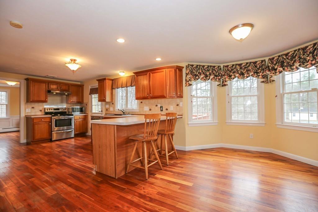 323 Sugar Road Bolton, MA 01740 - Photo 4 of 35 a kitchen with stainless steel appliances kitchen island granite countertop wooden floors and white cabinets