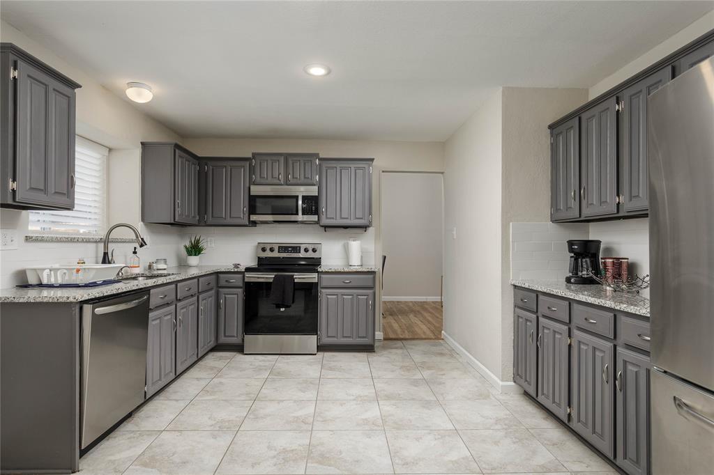 4108 Fryer Street The Colony, TX 75056 - Photo 14 of 27 a kitchen with stainless steel appliances granite countertop a stove top oven a sink dishwasher and a refrigerator
