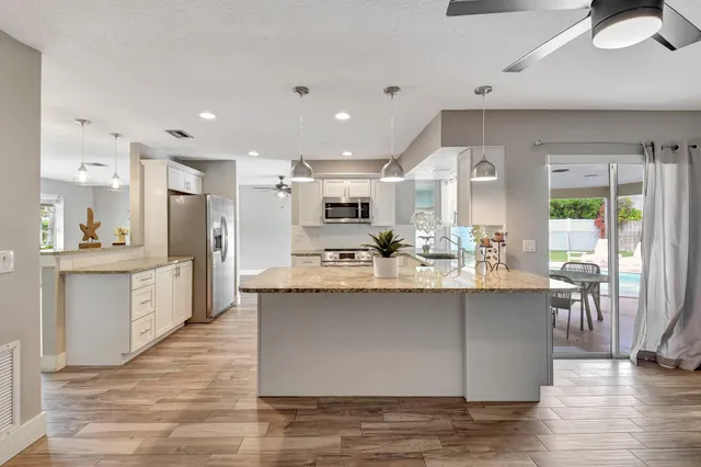 a view of kitchen with stainless steel appliances granite countertop stove top oven and cabinets