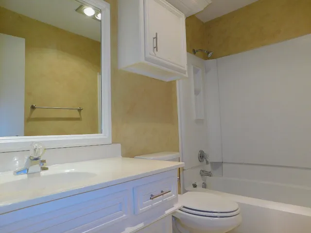 a bathroom with a bathtub shower sink vanity mirror and toilet