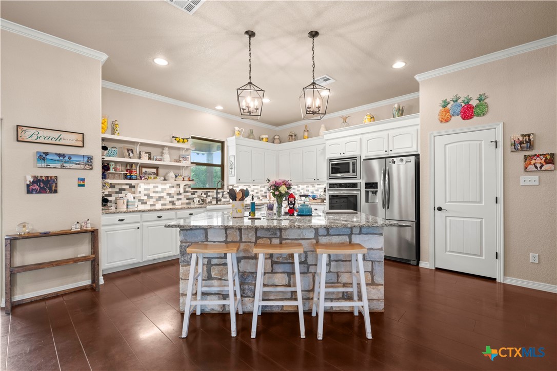 2649 Bowles Ranch Road Belton, TX 76513 - Photo 7 of 36 a kitchen with stainless steel appliances kitchen island granite countertop a table chairs and wooden floor