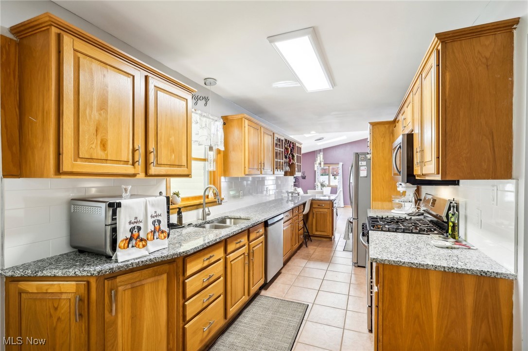 753 Ewing Road Youngstown, OH 44512 - Photo 18 of 47 Kitchen with sink, light tile patterned floors, tasteful backsplash, light stone counters, and stainless steel appliances