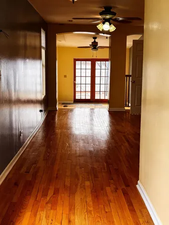 a view of empty room with wooden floor and fan