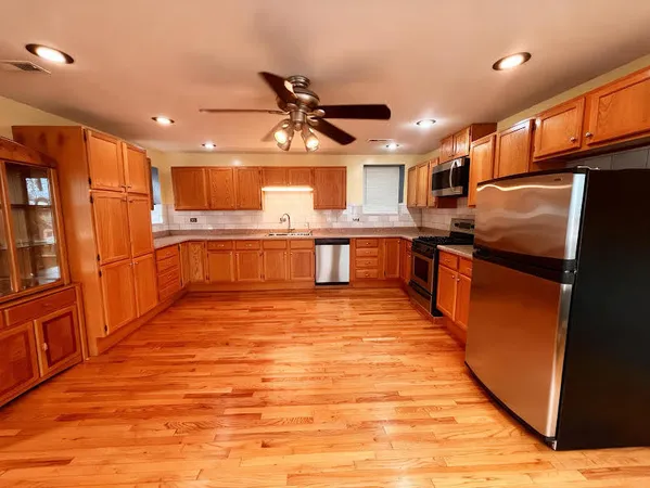 a large kitchen with stainless steel appliances granite countertop a sink and wooden cabinets