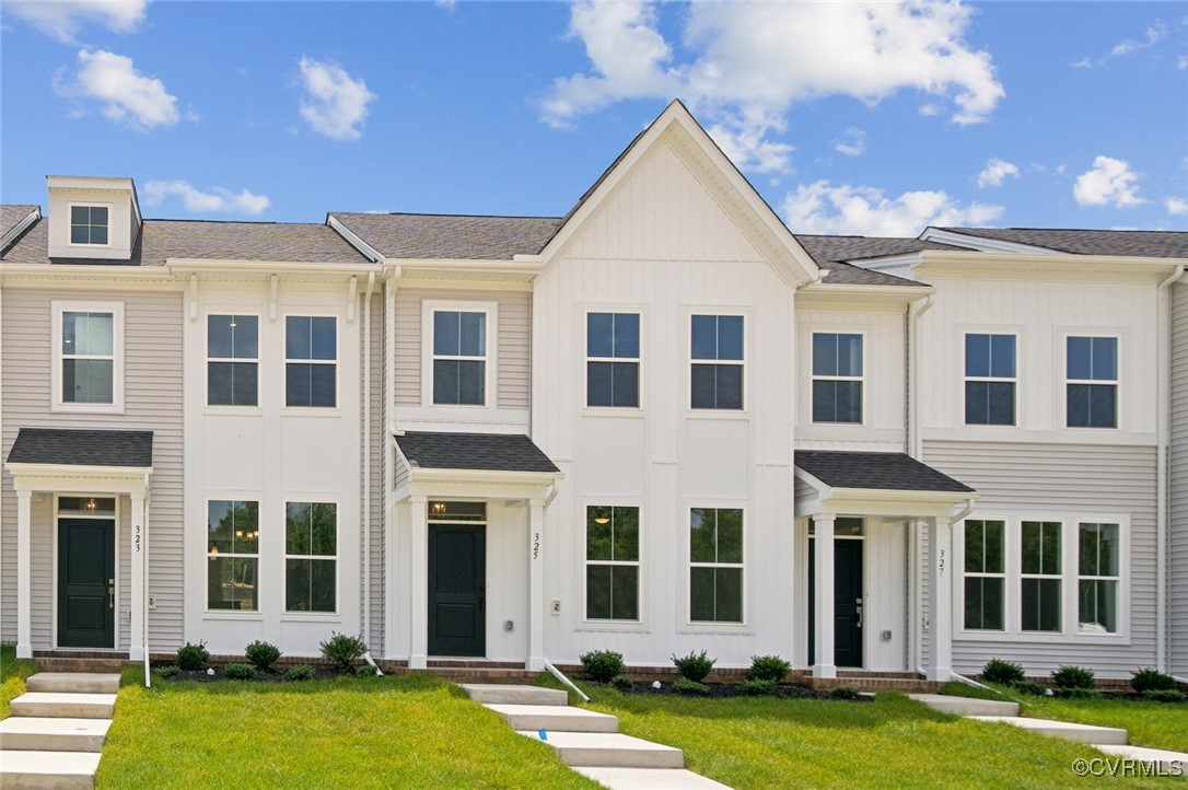 front view of a brick building with a yard and large trees