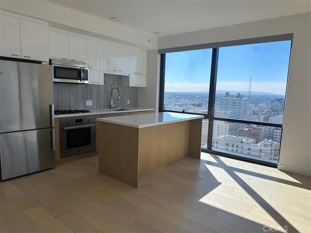 a kitchen with stainless steel appliances granite countertop a refrigerator a sink a stove top oven a counter space and cabinets