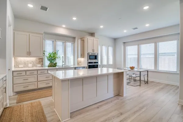 a kitchen with white cabinets and window