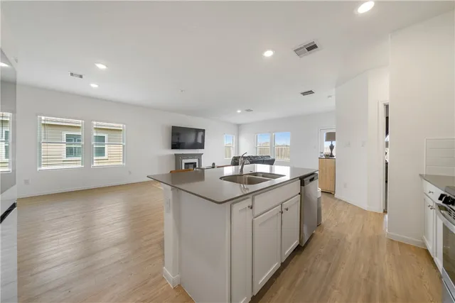 a kitchen with granite countertop a sink appliances cabinets and wooden floor