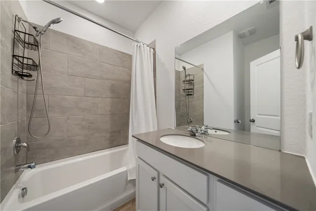 a bathroom with a granite countertop sink a mirror and a bathtub