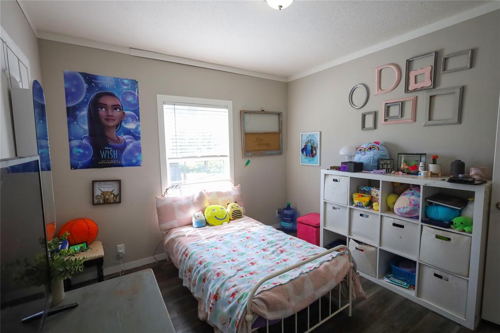 55 County Road West Comanche, TX 76442 - Photo 22 of 36 a bedroom with a bed a dresser and paintings on the wall