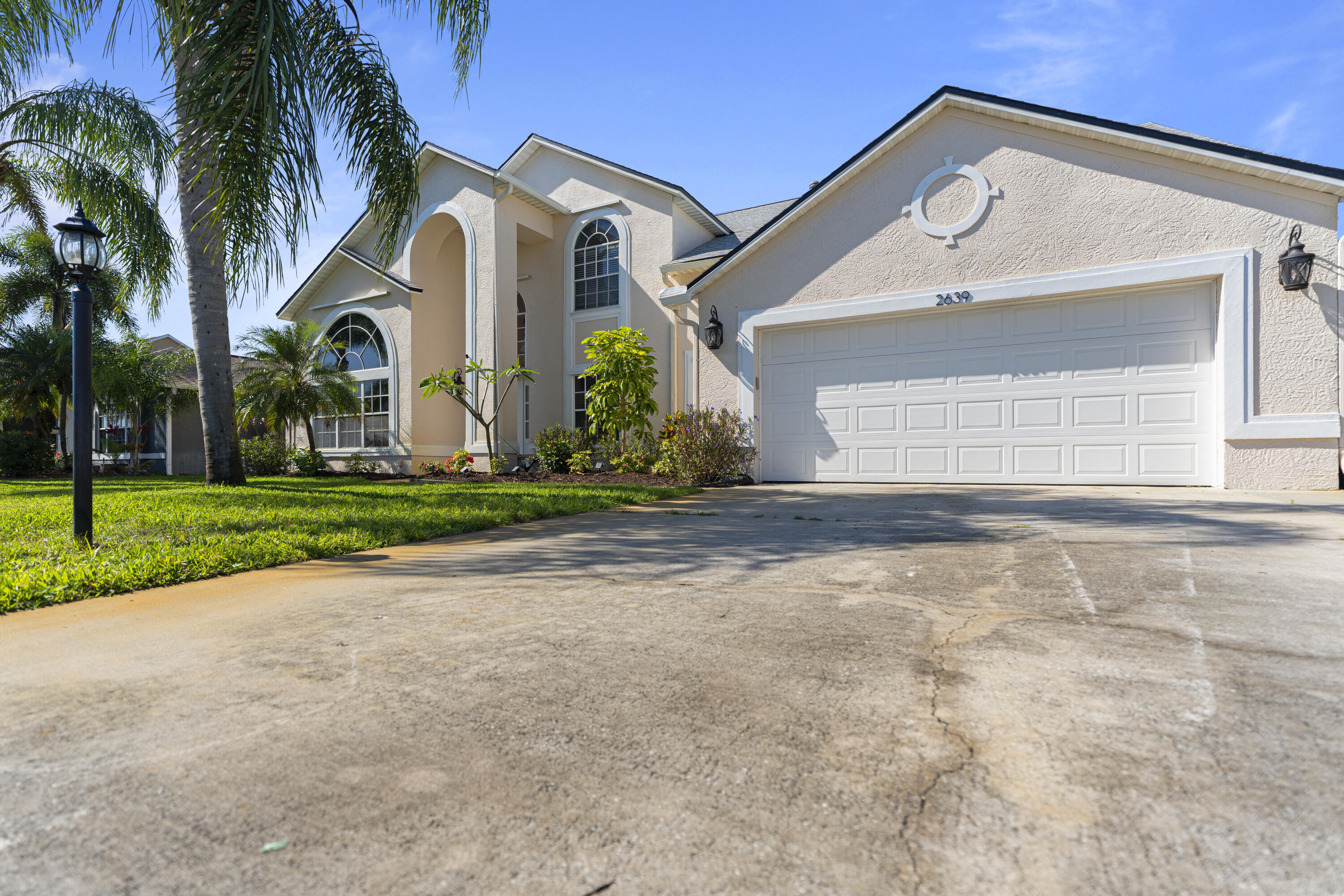 2639 Lowell Circle Melbourne, FL 32935 - Photo 46 of 46 a front view of yellow house with a yard and palm trees