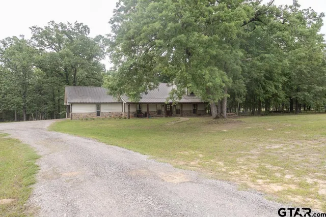a front view of a house with a garden and trees