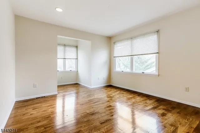 an empty room with wooden floor cabinet and windows