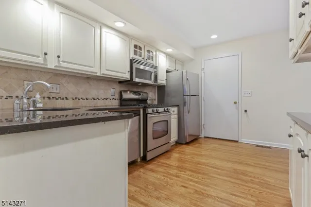 a kitchen with stainless steel appliances granite countertop a refrigerator and a stove