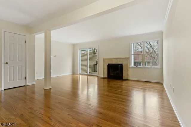 an empty room with wooden floor fireplace and windows